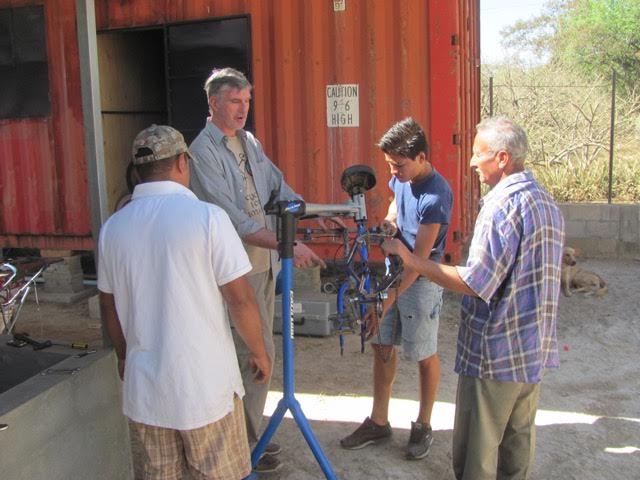 MARK WITH HIS 3 BIKE MECHANIC TRAINEES. THE CONTAINER BIKE SHOP IN BACKGROUND